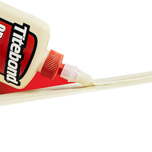 Titebond Original Wood Glue bottle with red cap dispensing pale glue onto light wood surface