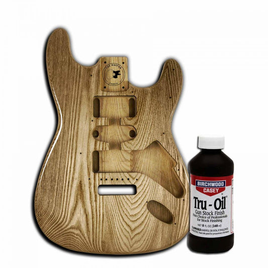 Tru Oil 240mL bottle displayed next to unfinished wooden guitar body showing wood grain detail