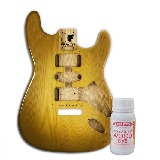 Yellow alcohol-based dye bottle next to guitar body showing warm golden wood finish