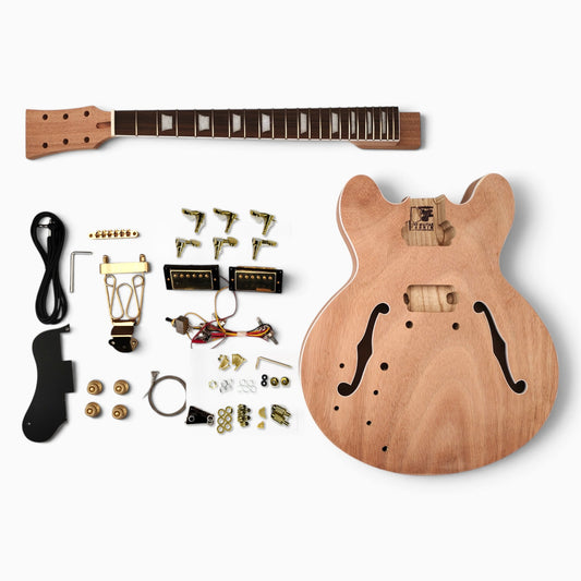 Left handed semi hollow kit laid flat: unfinished mahogany body with f-holes, neck, gold humbuckers, tuners, trapeze tailpiece, wiring